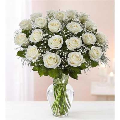White roses arranged in a clear glass vase with baby's breath
