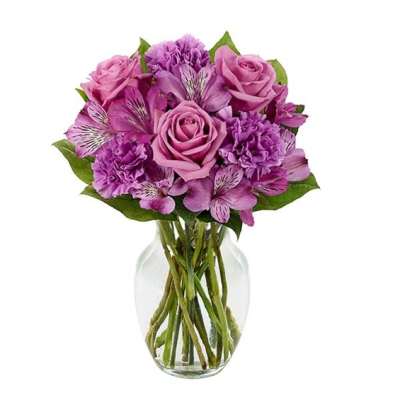 Pink and purple bouquet of roses and carnations in a clear glass vase
