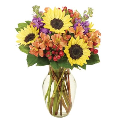 Bouquet of sunflowers, orange alstroemeria, and purple flowers in a glass vase