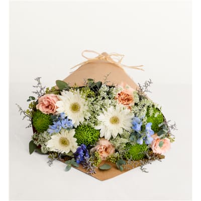 Mixed bouquet of white daisies, peach roses, and blue flowers wrapped in kraft paper