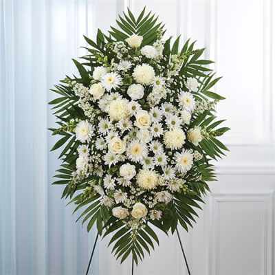 White funeral standing spray with mixed blooms and palm fronds
