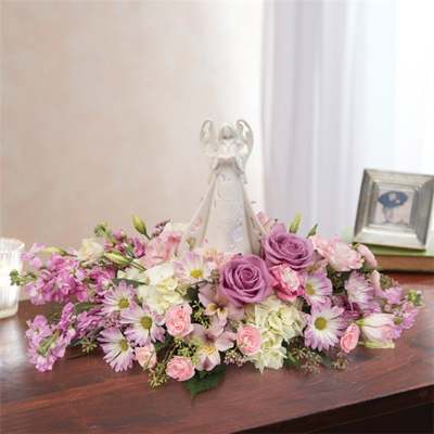 Pink and lavender floral arrangement around a white angel figurine