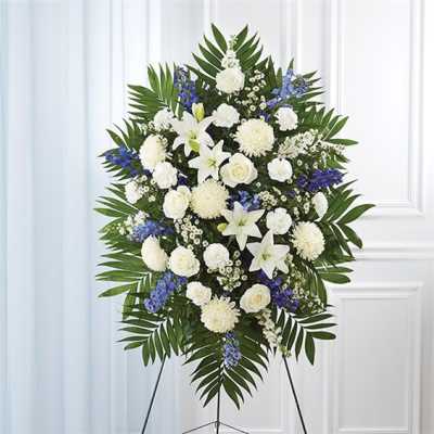 Standing floral spray with white lilies, roses, and blue accents