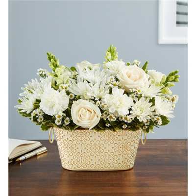 White floral arrangement in a patterned cream basket on a table