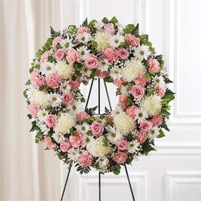 Pink and white floral wreath on a black stand