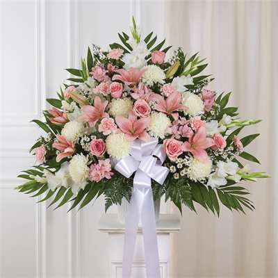 Pink and white floral spray with a white ribbon bow on a stand