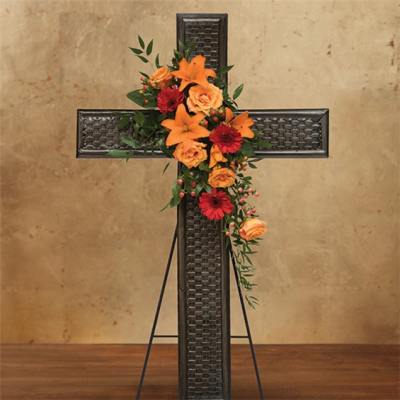 Floral cross arrangement with orange lilies, roses, and red daisies