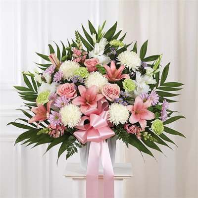Pink and white floral arrangement in a vase with a pink ribbon
