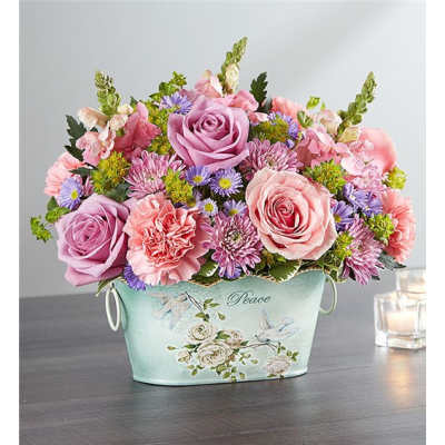 Pink and lavender flower arrangement in a mint container with "Peace" text