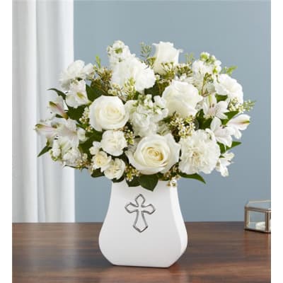 White floral arrangement in a white vase with a cross emblem