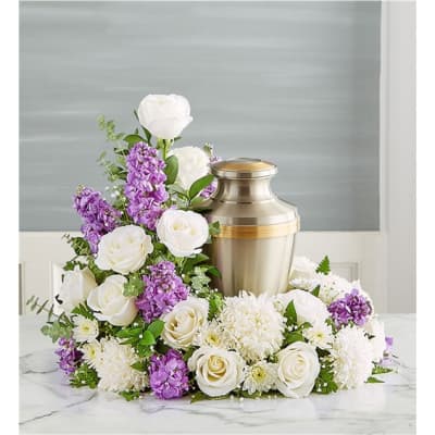 White and purple floral arrangement around a silver urn