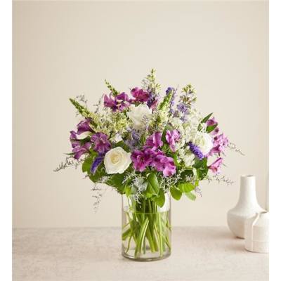 Mixed bouquet of purple and white flowers in a clear glass vase