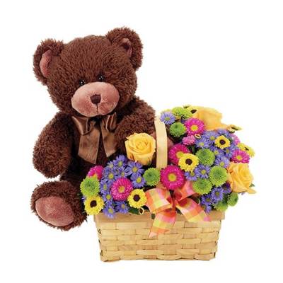 Teddy bear beside a basket of colorful flowers