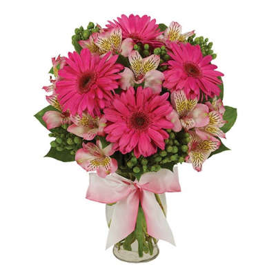 Pink gerbera daisies and alstroemeria in a glass vase with a pink ribbon