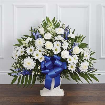 White daisies and roses in a white vase with a blue ribbon