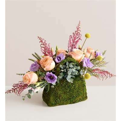 Peach and lavender roses in a moss-covered container