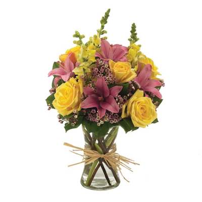 Bouquet of yellow roses and pink lilies in a glass vase