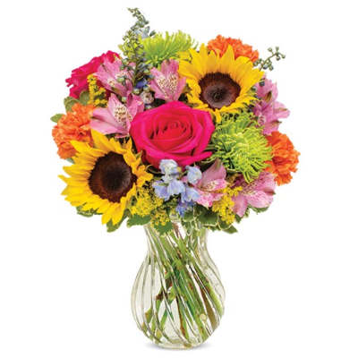 Colorful mixed bouquet in a clear glass vase with sunflowers and a pink rose