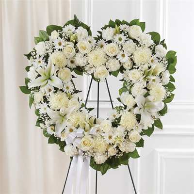 Heart-shaped white floral wreath on a stand with a ribbon