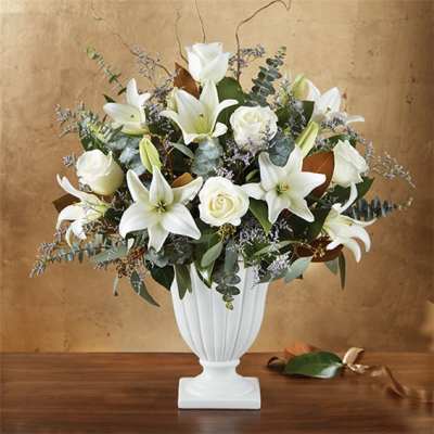 White lilies and roses arranged in a white pedestal vase