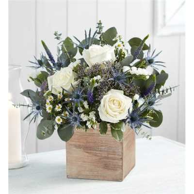 White roses and blue thistle in a wooden box vase