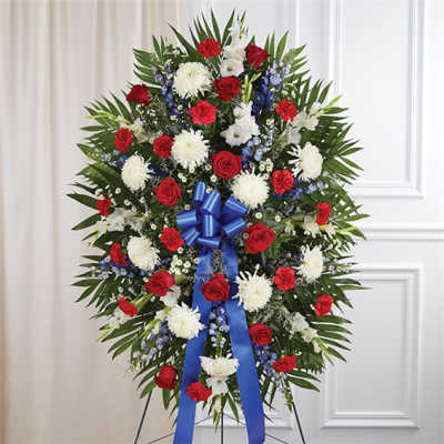 Standing floral spray with red roses, white mums, and blue ribbon
