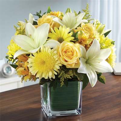 Yellow and white flower arrangement in a square glass vase