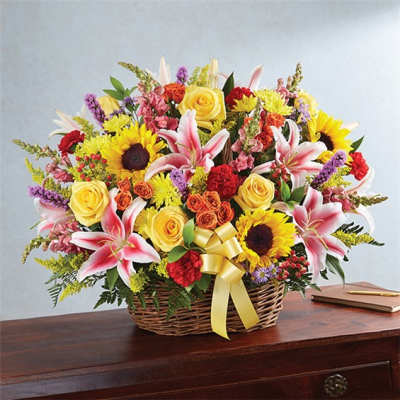 Mixed bouquet in a wicker basket with sunflowers, roses, and lilies