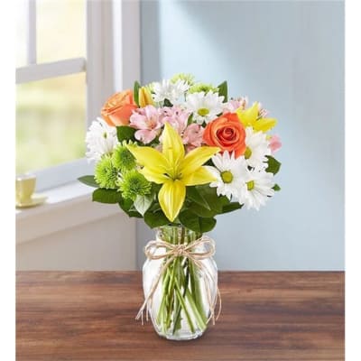 Mixed bouquet of lilies, roses, and daisies in a glass vase