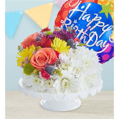 Colorful birthday bouquet in a white pedestal bowl with a foil balloon