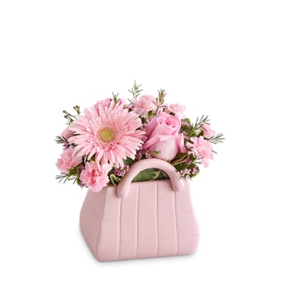 Pink flowers arranged in a pink handbag-shaped container