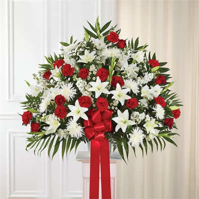 Large red and white floral standing arrangement with a red ribbon bow