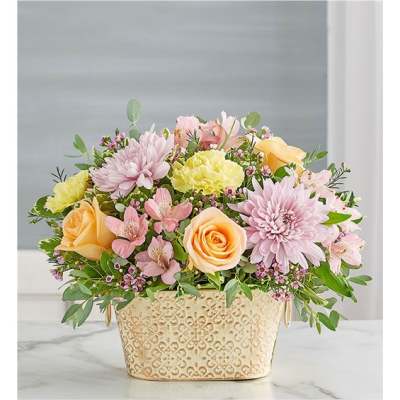 Pastel flower arrangement in a decorative cream container