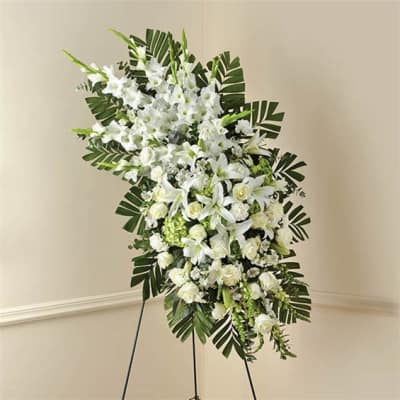 Tall white floral standing spray with palm leaves on an easel