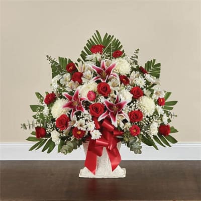 Red and white floral arrangement in a white vase with a red ribbon