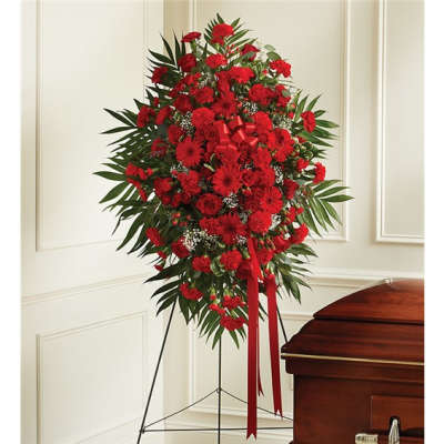Standing red floral spray on an easel beside a casket