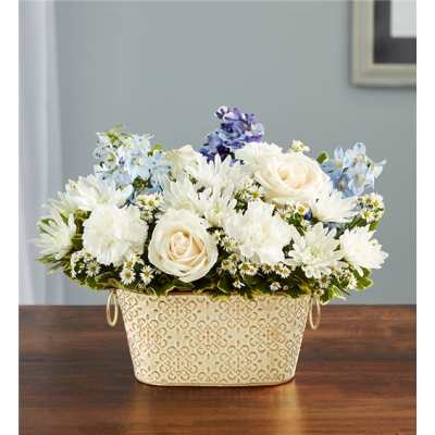 White and pale blue flowers arranged in a patterned metal basket