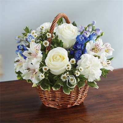 Basket arrangement of white roses, blue flowers, and white daisies