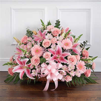 Pink lilies and roses in a basket with a pink ribbon