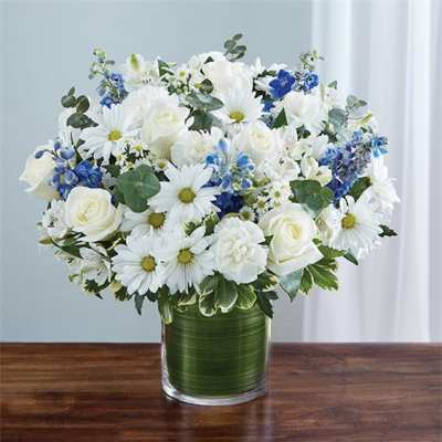 White roses and daisies in a green glass vase