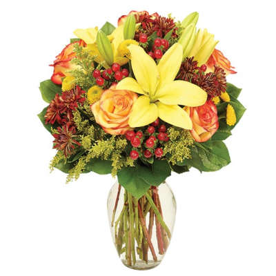 Bouquet of yellow lilies and orange roses in a clear glass vase