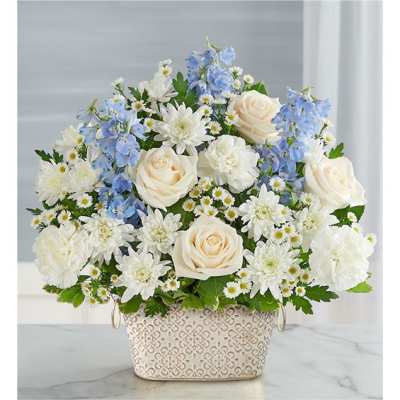 White roses and blue flowers arranged in a patterned basket