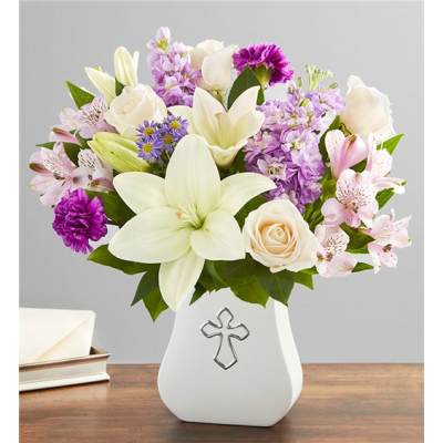 White lilies and roses in a white vase with a cross emblem