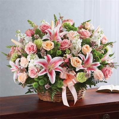 Basket arrangement of pink roses and lilies with a ribbon