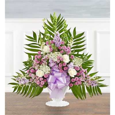 Lavender and white floral arrangement in a white pedestal vase with a purple bow