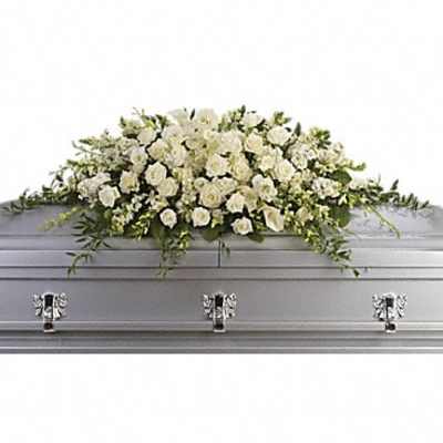 White rose casket spray with trailing greenery on a gray casket