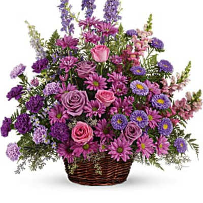 Purple and pink mixed flower arrangement in a wicker basket