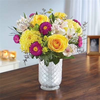 Mixed bouquet of yellow and purple flowers in a white vase