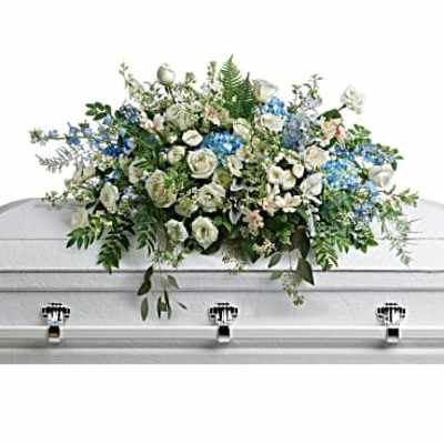 White and blue floral casket spray on a white casket