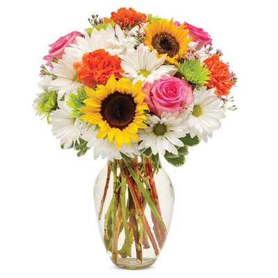 Mixed bouquet of sunflowers, daisies, roses, and carnations in a glass vase